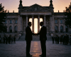 Two men shaking hands silhouetted against a grand government building at sunset
